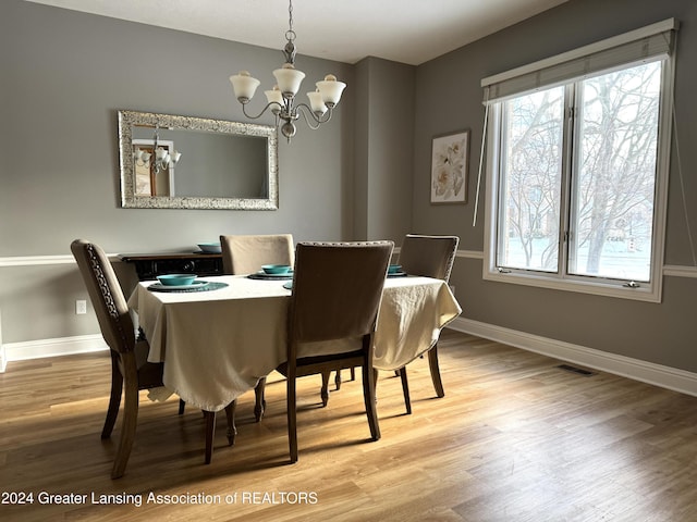 dining space featuring wood-type flooring and a chandelier