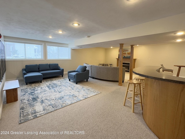 living room featuring bar, light colored carpet, and a textured ceiling