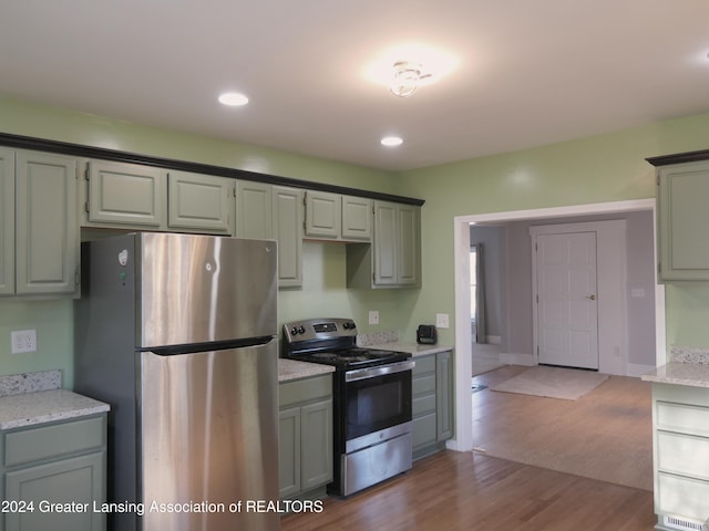 kitchen featuring hardwood / wood-style flooring, light stone countertops, and appliances with stainless steel finishes