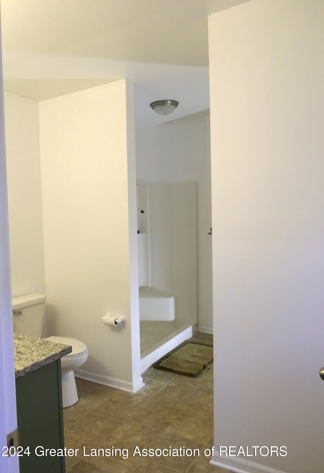 bathroom with a shower, vanity, toilet, and tile patterned flooring