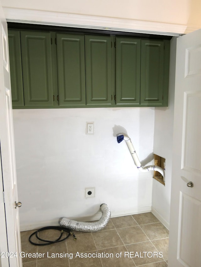 laundry area featuring electric dryer hookup, hookup for a washing machine, light tile patterned flooring, and cabinets