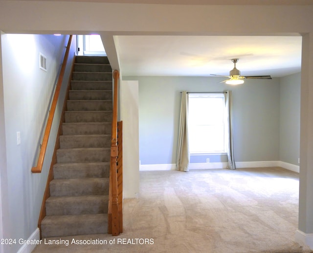 staircase with ceiling fan and carpet floors