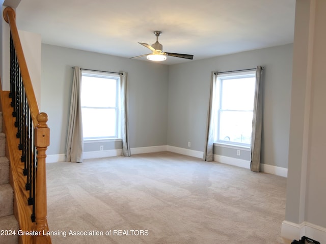 carpeted spare room featuring ceiling fan and a healthy amount of sunlight