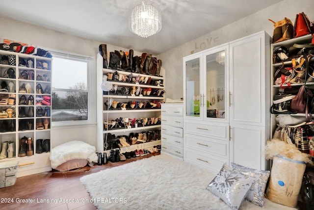 walk in closet featuring hardwood / wood-style flooring and a chandelier