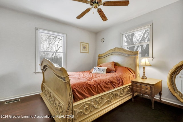 bedroom with ceiling fan, dark hardwood / wood-style flooring, and multiple windows