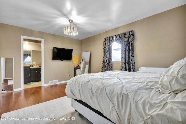 bedroom featuring a notable chandelier, ensuite bath, and light wood-type flooring