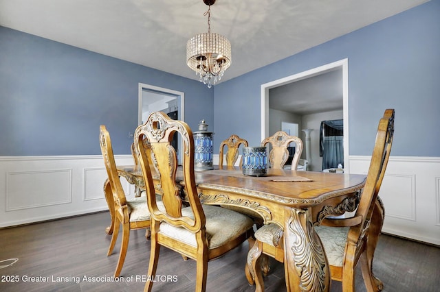 dining area featuring dark wood-type flooring and an inviting chandelier