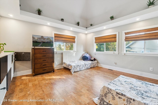 bedroom featuring a towering ceiling and light hardwood / wood-style flooring