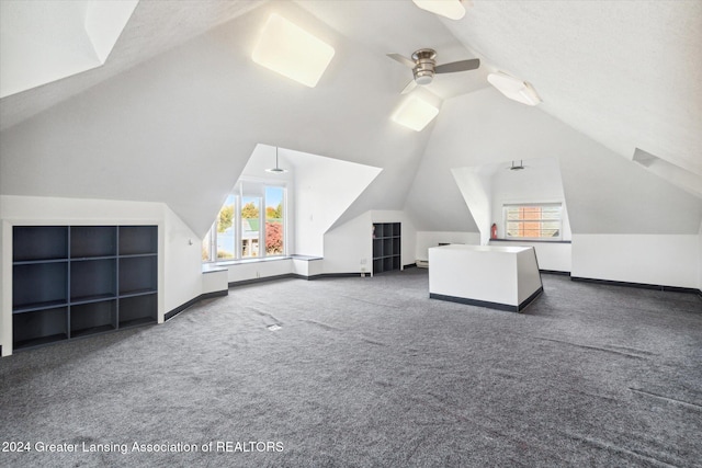 bonus room featuring ceiling fan, plenty of natural light, dark carpet, and lofted ceiling