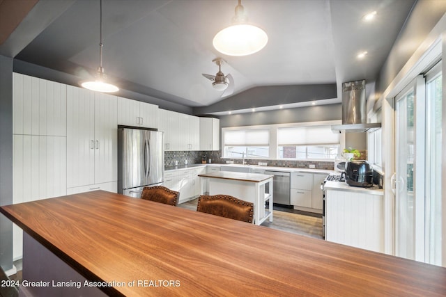 kitchen featuring white cabinets, decorative light fixtures, vaulted ceiling, and stainless steel appliances