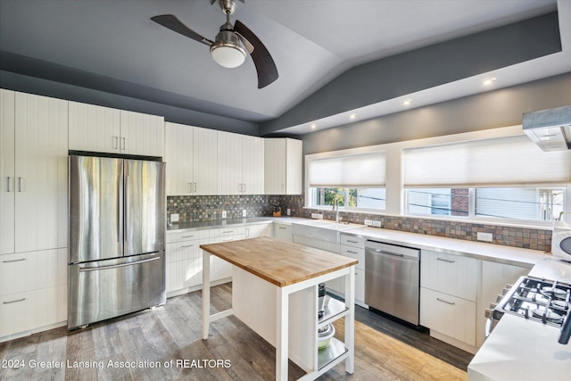 kitchen featuring butcher block counters, sink, a center island, vaulted ceiling, and appliances with stainless steel finishes