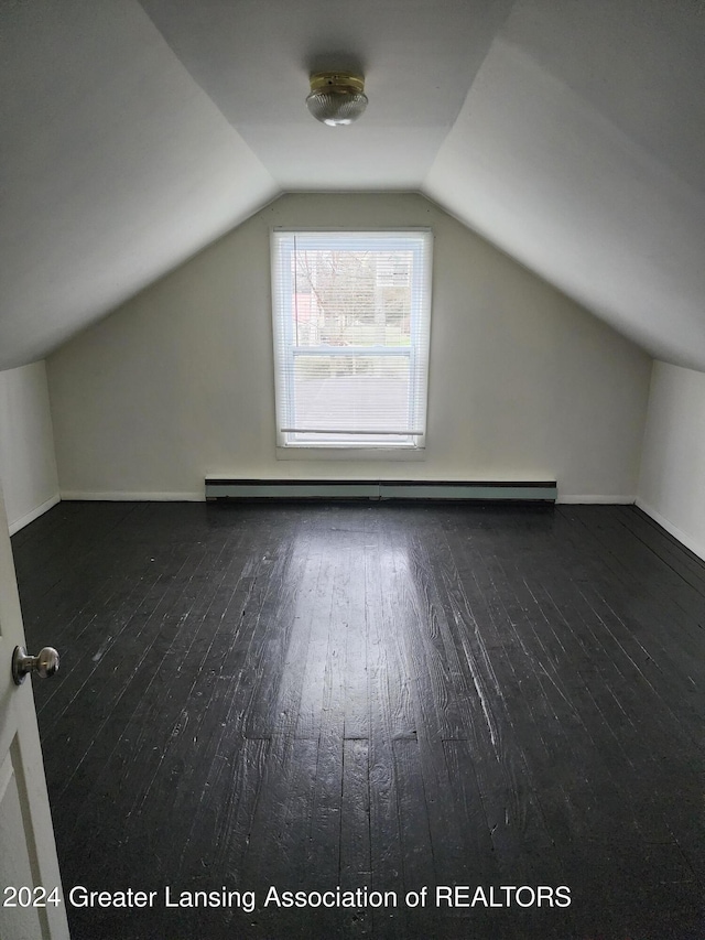 additional living space featuring a baseboard heating unit, vaulted ceiling, and dark wood-type flooring