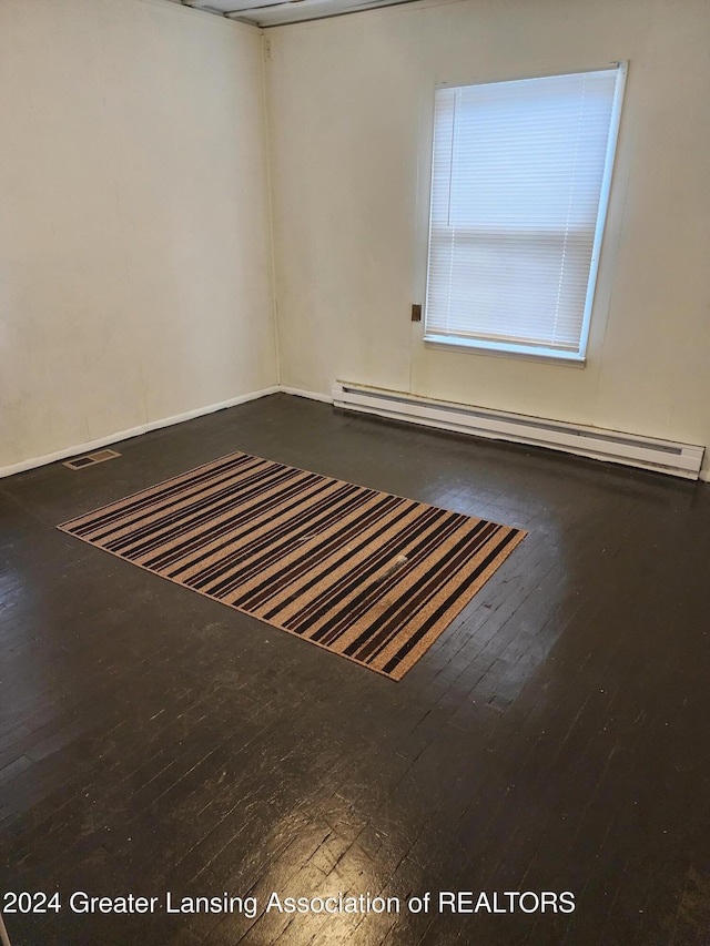 spare room featuring hardwood / wood-style floors and a baseboard heating unit