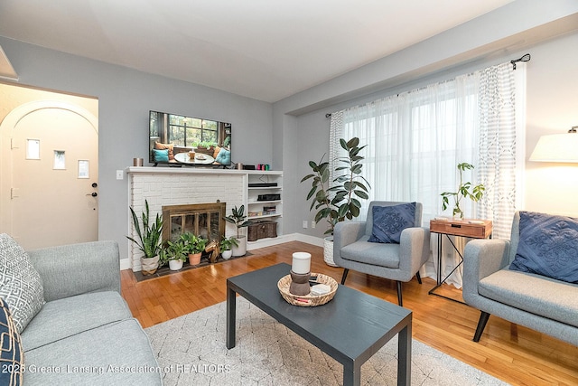 living room featuring wood-type flooring and a brick fireplace