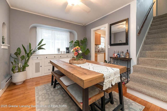 dining room with baseboard heating, ceiling fan, ornamental molding, and light wood-type flooring