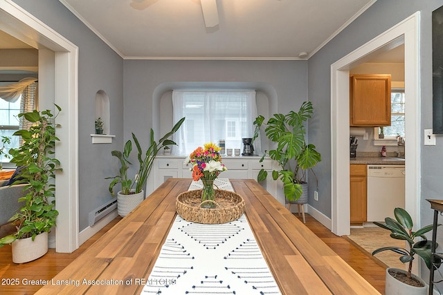 dining space featuring ornamental molding, light wood-type flooring, and a baseboard heating unit