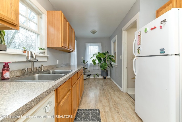 kitchen with sink, white appliances, and light hardwood / wood-style floors