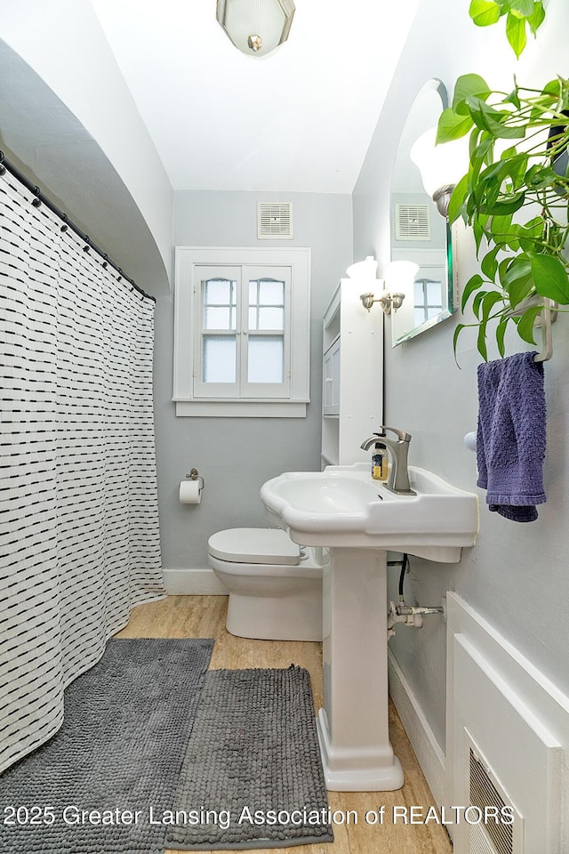 bathroom featuring a shower with curtain, hardwood / wood-style flooring, and toilet