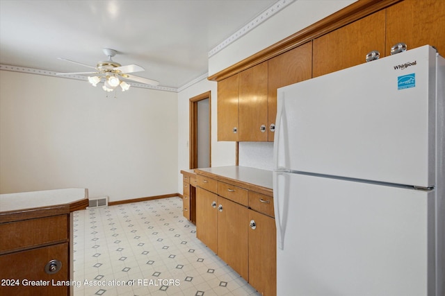 kitchen featuring ceiling fan, crown molding, and white fridge