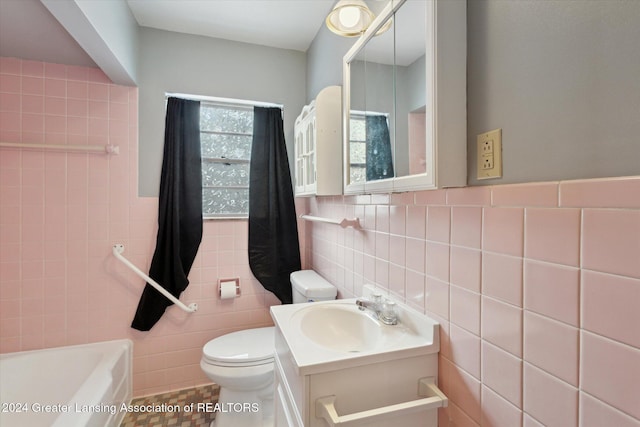 bathroom with vanity, tile patterned floors, toilet, a tub to relax in, and tile walls