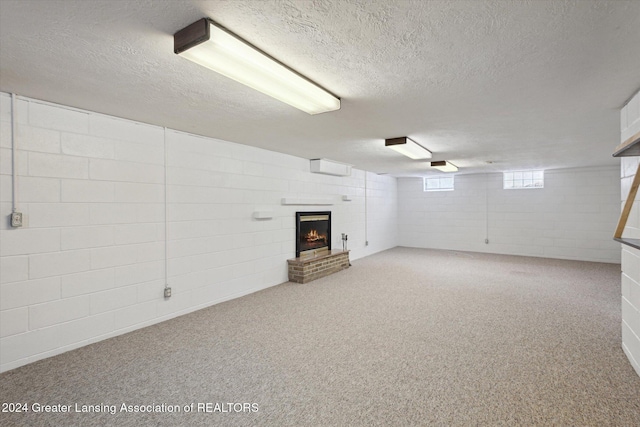 basement featuring carpet, a textured ceiling, and a brick fireplace