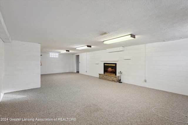 basement with a wall mounted AC, carpet, a textured ceiling, and a brick fireplace