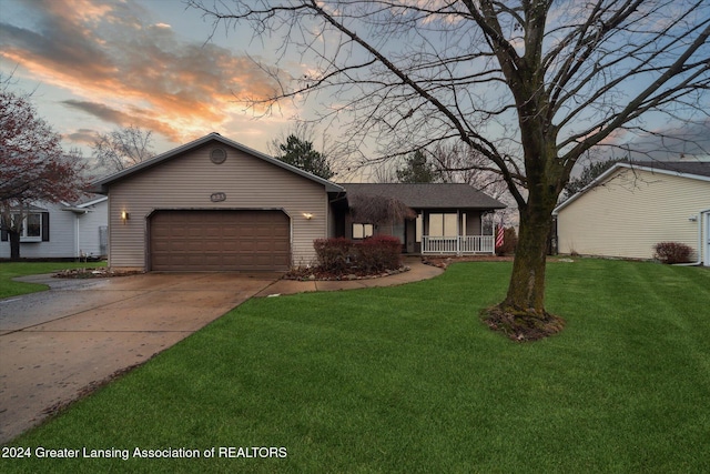 ranch-style home with a yard, covered porch, and a garage