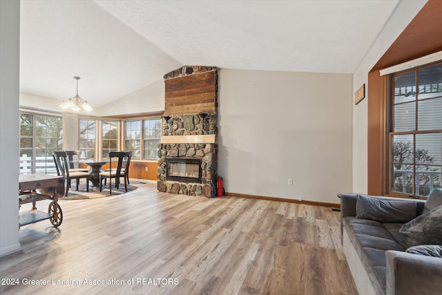 living room with lofted ceiling, a fireplace, a chandelier, and hardwood / wood-style floors