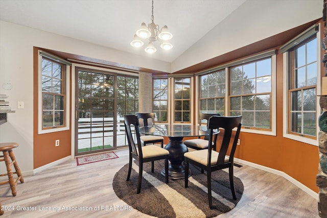 dining room featuring light wood-type flooring, vaulted ceiling, a chandelier, and plenty of natural light