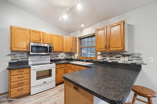 kitchen with kitchen peninsula, electric stove, a breakfast bar, lofted ceiling, and sink