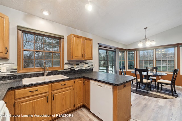 kitchen featuring vaulted ceiling, white dishwasher, sink, an inviting chandelier, and decorative light fixtures