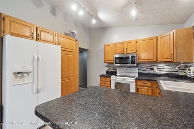 kitchen featuring sink, a textured ceiling, vaulted ceiling, white appliances, and tasteful backsplash