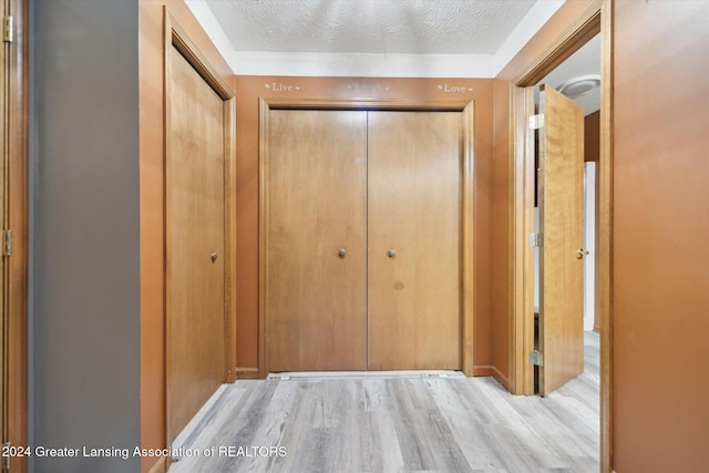 hallway featuring a textured ceiling and light hardwood / wood-style floors