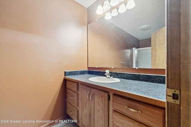 bathroom featuring a shower with door and vanity