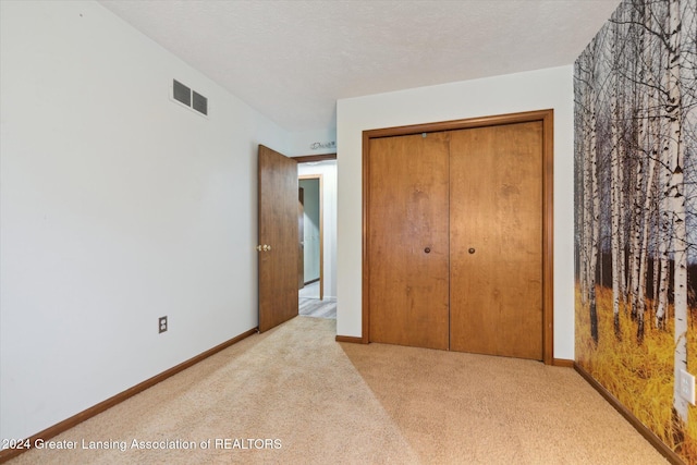 carpeted bedroom featuring a textured ceiling and a closet