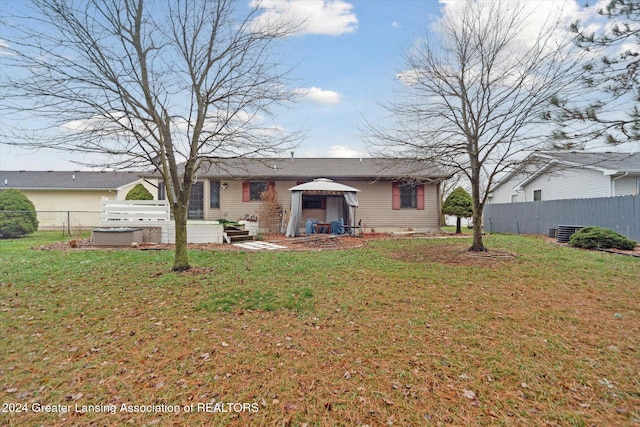 rear view of property with a hot tub and a lawn