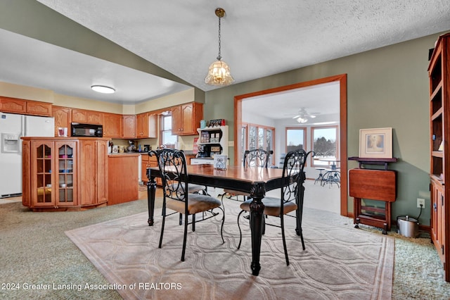 dining room with a textured ceiling, ceiling fan with notable chandelier, and light carpet