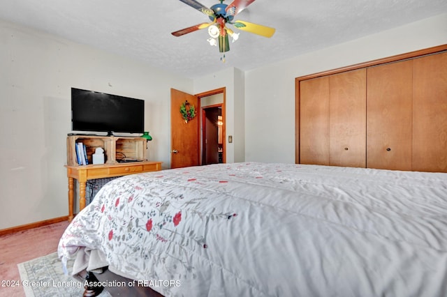 carpeted bedroom with ceiling fan, a closet, and a textured ceiling