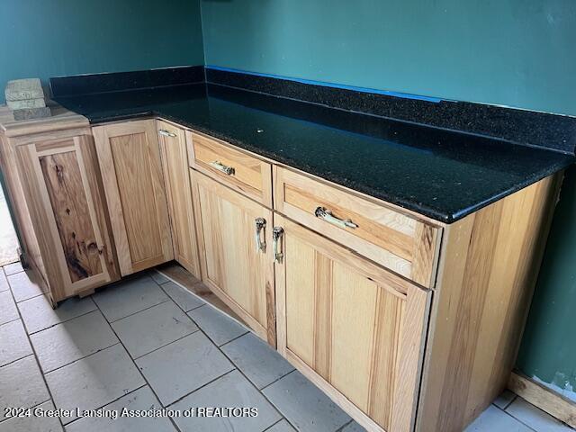 kitchen with dark stone countertops, light brown cabinetry, and light tile patterned flooring