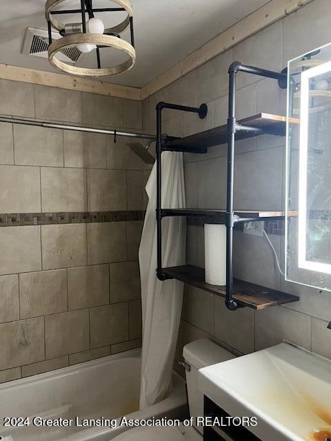 bathroom with shower / bathtub combination with curtain and sink