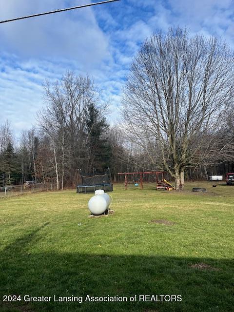 view of yard featuring a playground and a trampoline