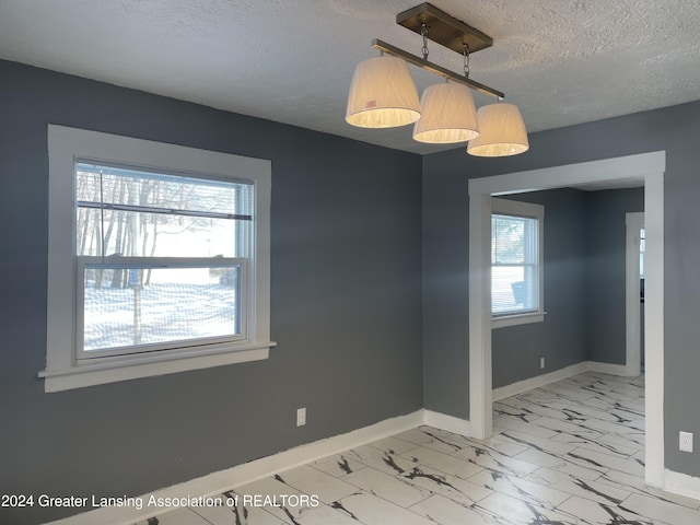 unfurnished dining area with a textured ceiling and a wealth of natural light