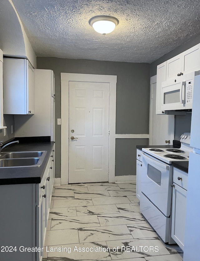 kitchen with white appliances, a textured ceiling, white cabinetry, and sink