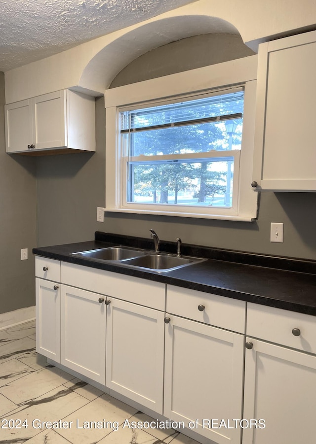 kitchen featuring sink, white cabinets, and a textured ceiling