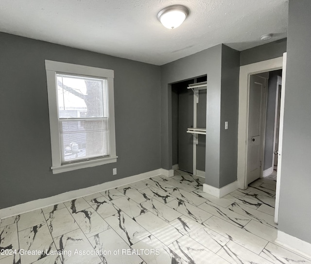 unfurnished bedroom with a textured ceiling and a closet