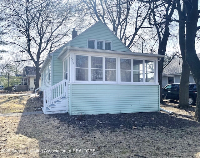 exterior space with entry steps, a chimney, and a sunroom