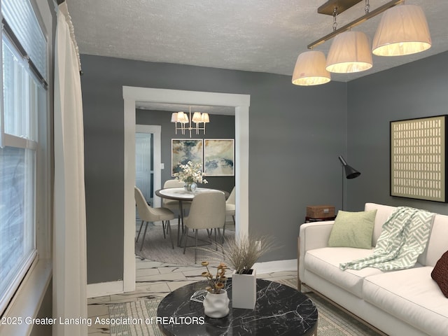 2519 S Washington Ave, Lansing, MI 48910 - living room featuring a chandelier, plenty of natural light, baseboards, a textured ceiling, and marble finish flooring