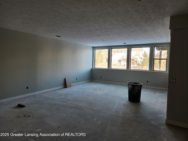 unfurnished room with a textured ceiling and baseboards