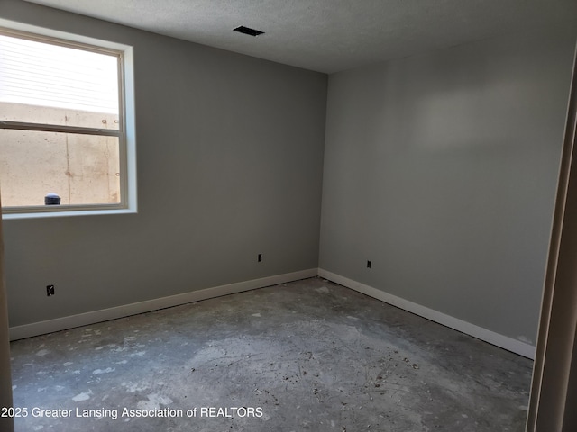 spare room featuring baseboards, concrete flooring, and a textured ceiling