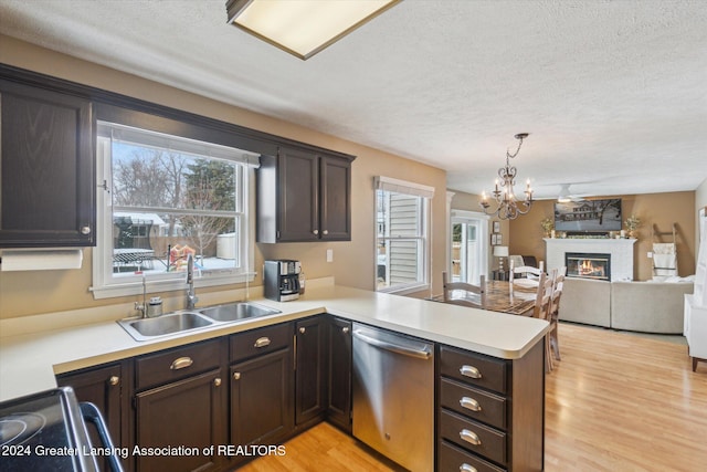 kitchen with light hardwood / wood-style floors, kitchen peninsula, hanging light fixtures, stainless steel dishwasher, and sink